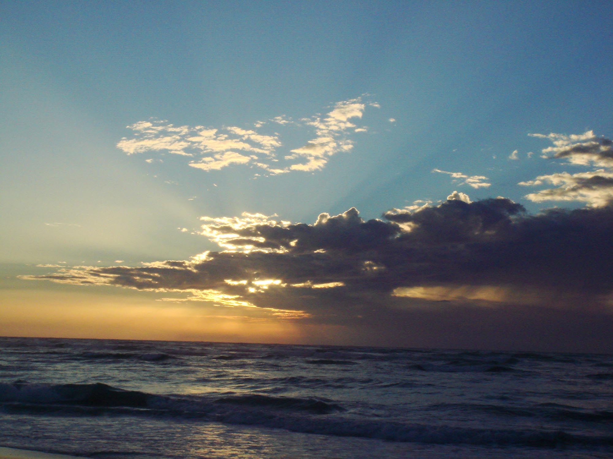 Luz de atardecer sobre el mar bajo un cielo de nubes